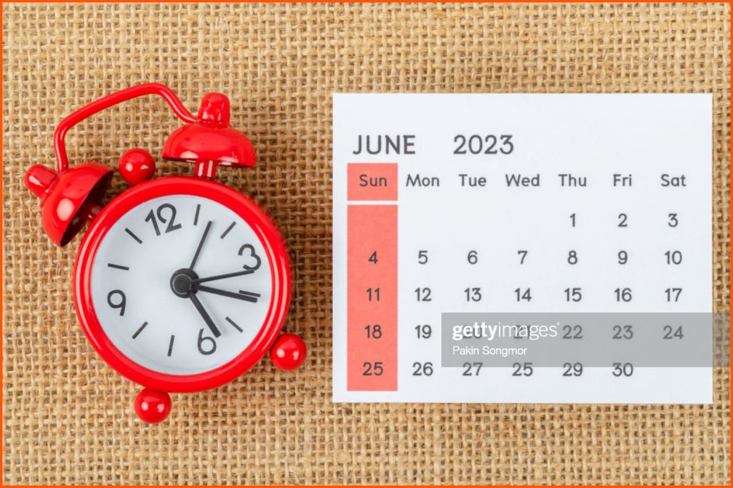 June calendar and big red alarm clock next to it.