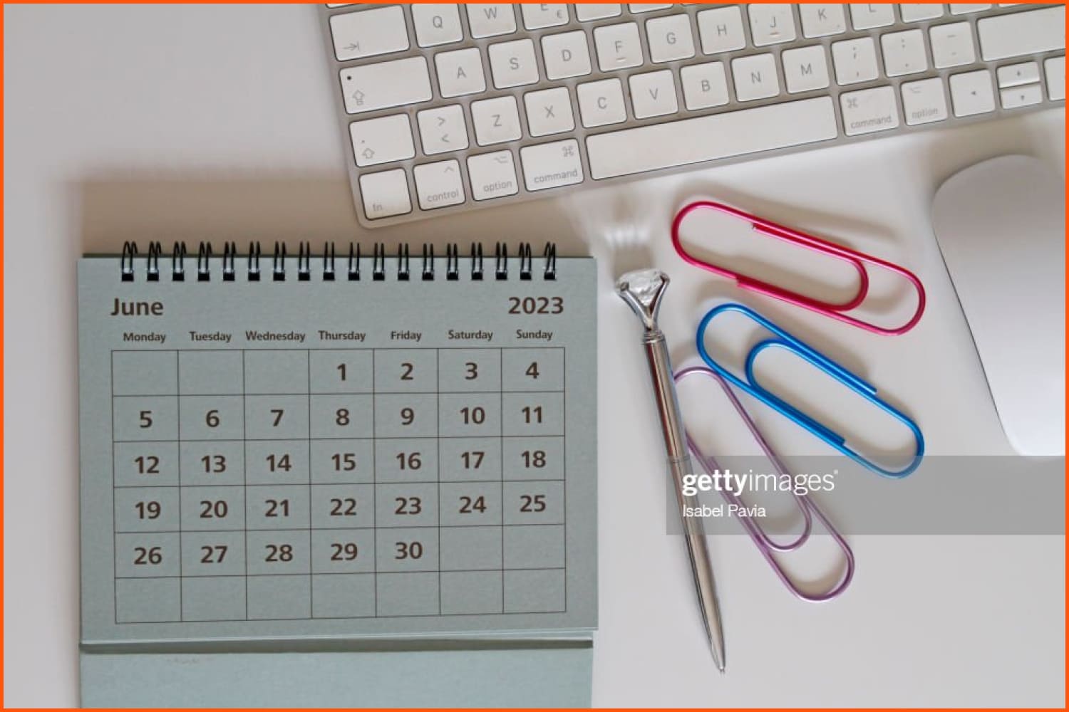 June calendar, pen, paper clips and keyboard on the table.