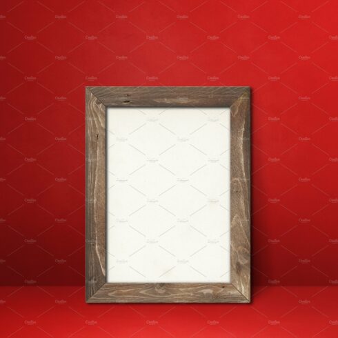 Wooden picture frame leaning on a red wall cover image.