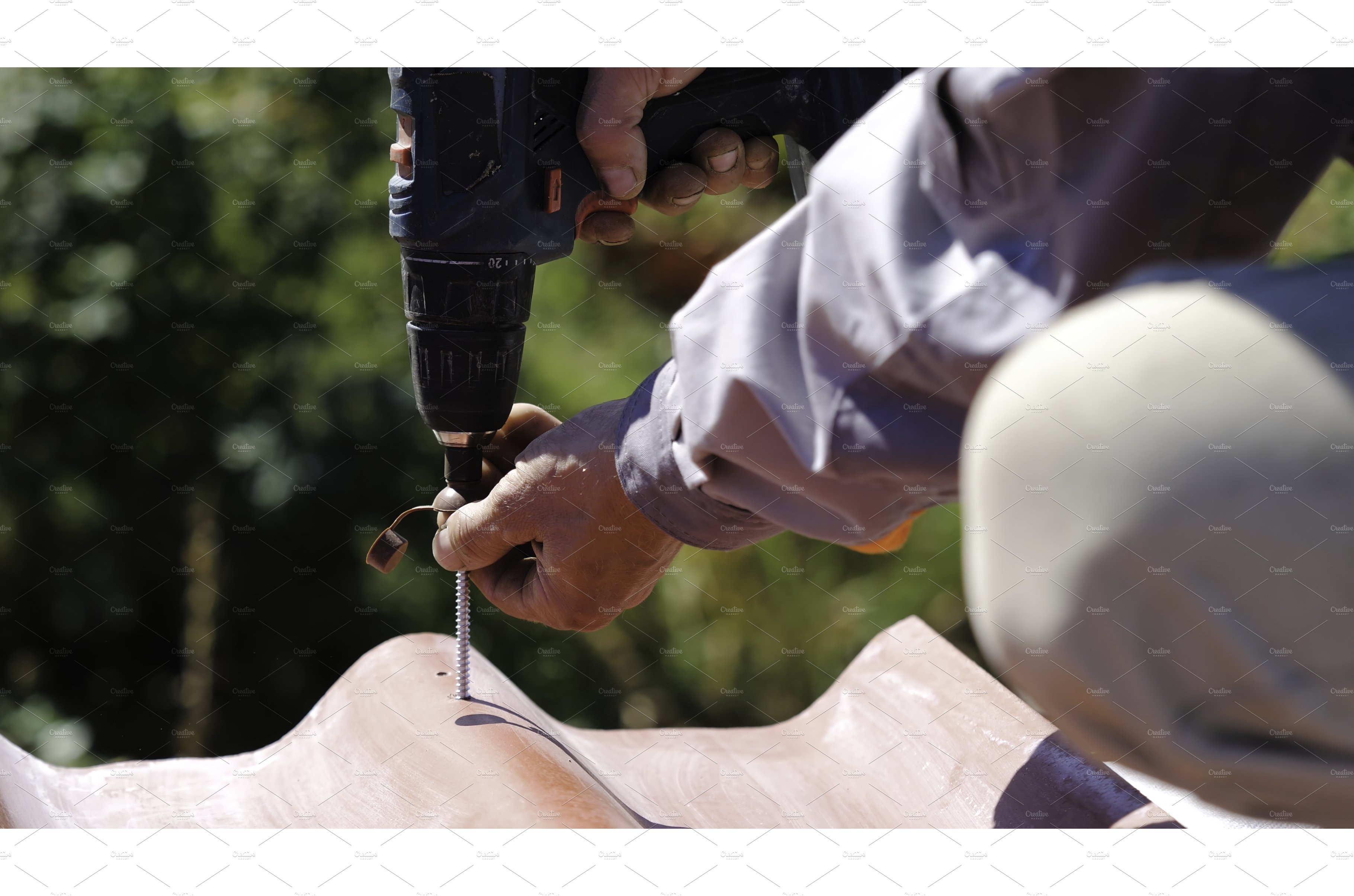 Man screws a screw into the roof cover image.