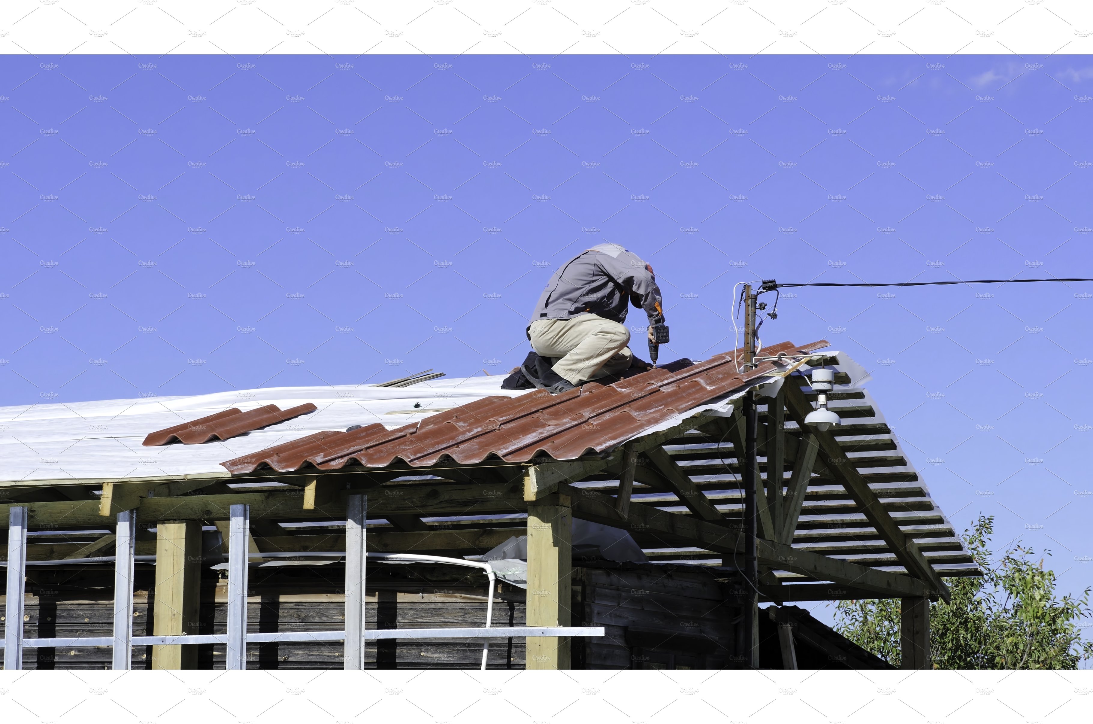 Man screws a screw into the roof cover image.