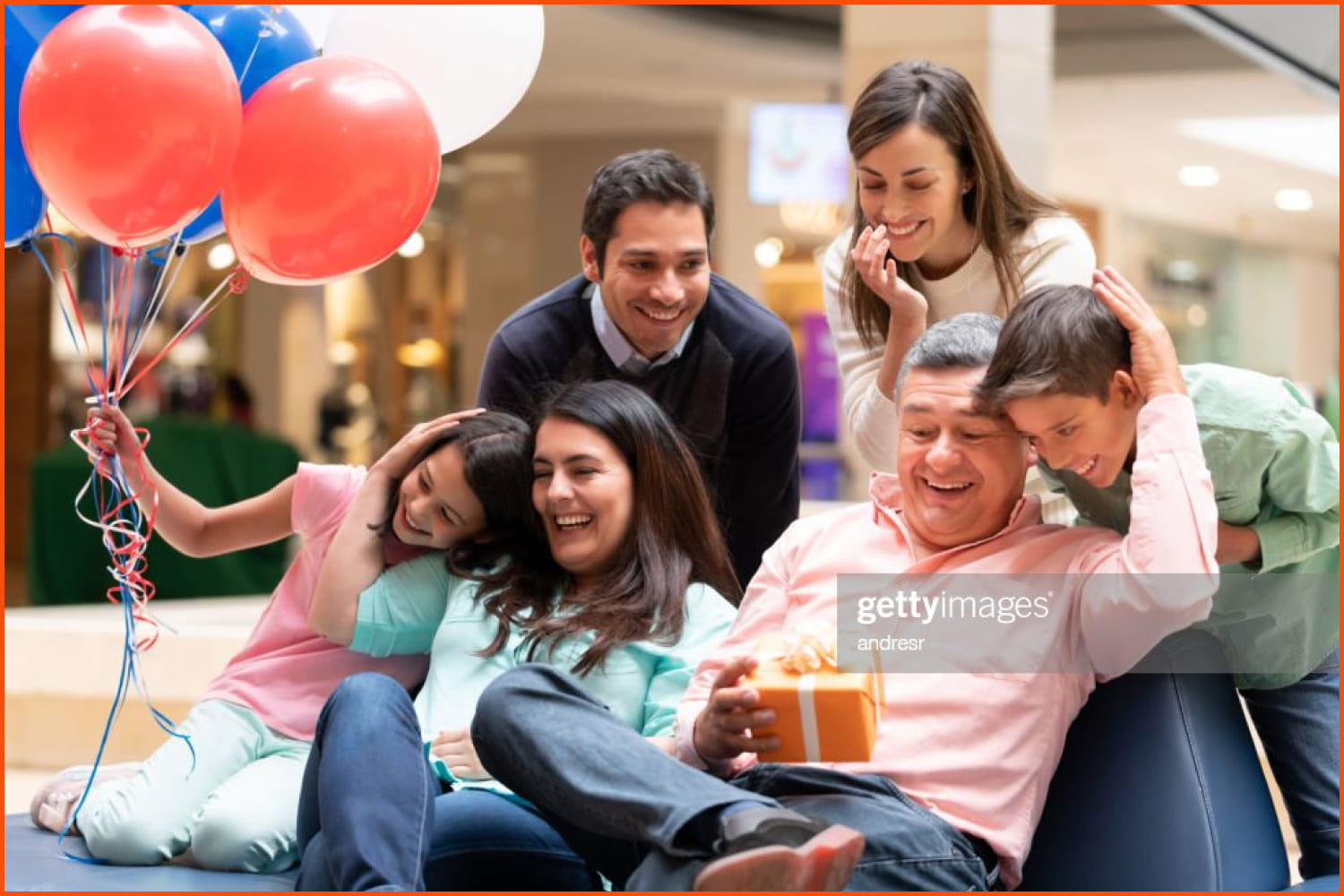 Happy grandfather celebrating Father's Day with his family at the mall and holding a gift while smiling a lifestyle concepts
