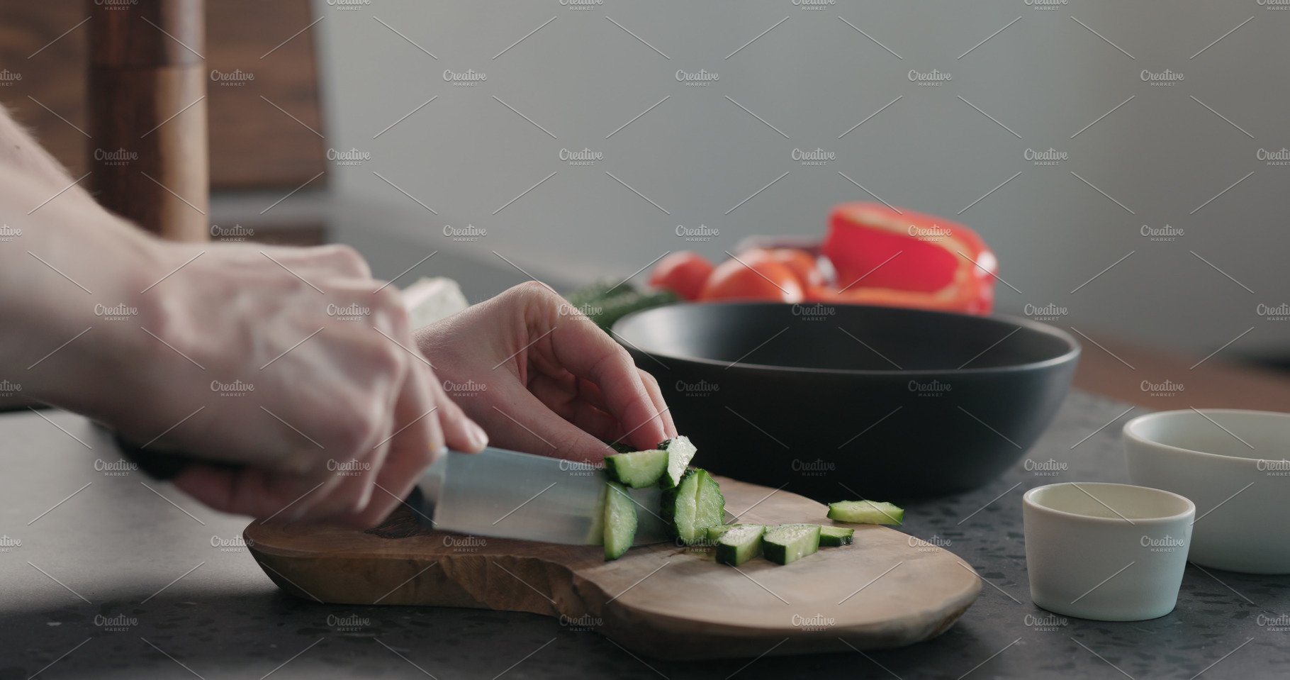 Man chopping cucumber on olive wood cover image.