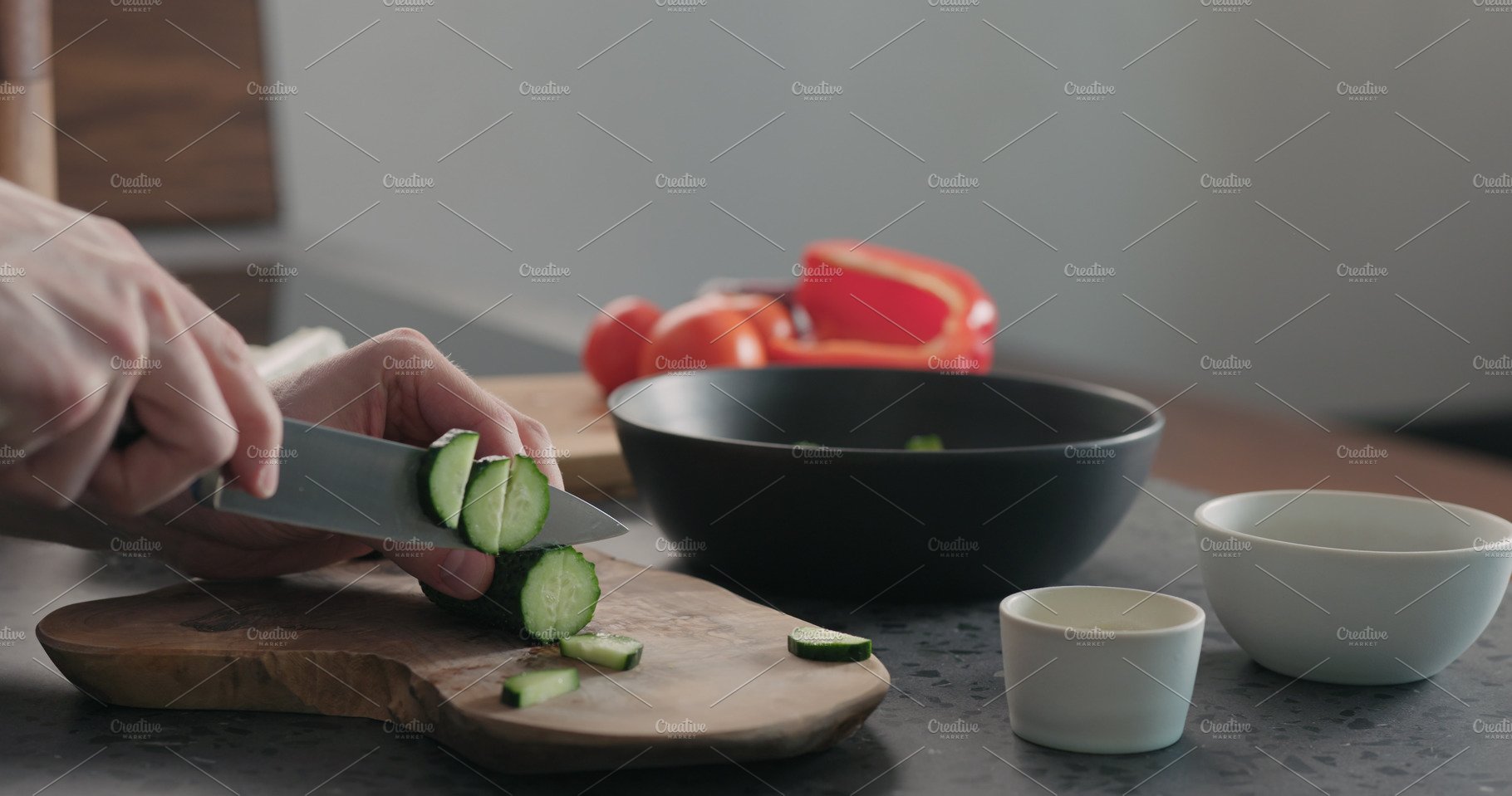 Man chopping cucumber on olive wood cover image.