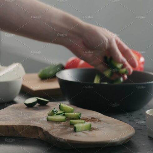 Man chopping cucumber on olive wood cover image.