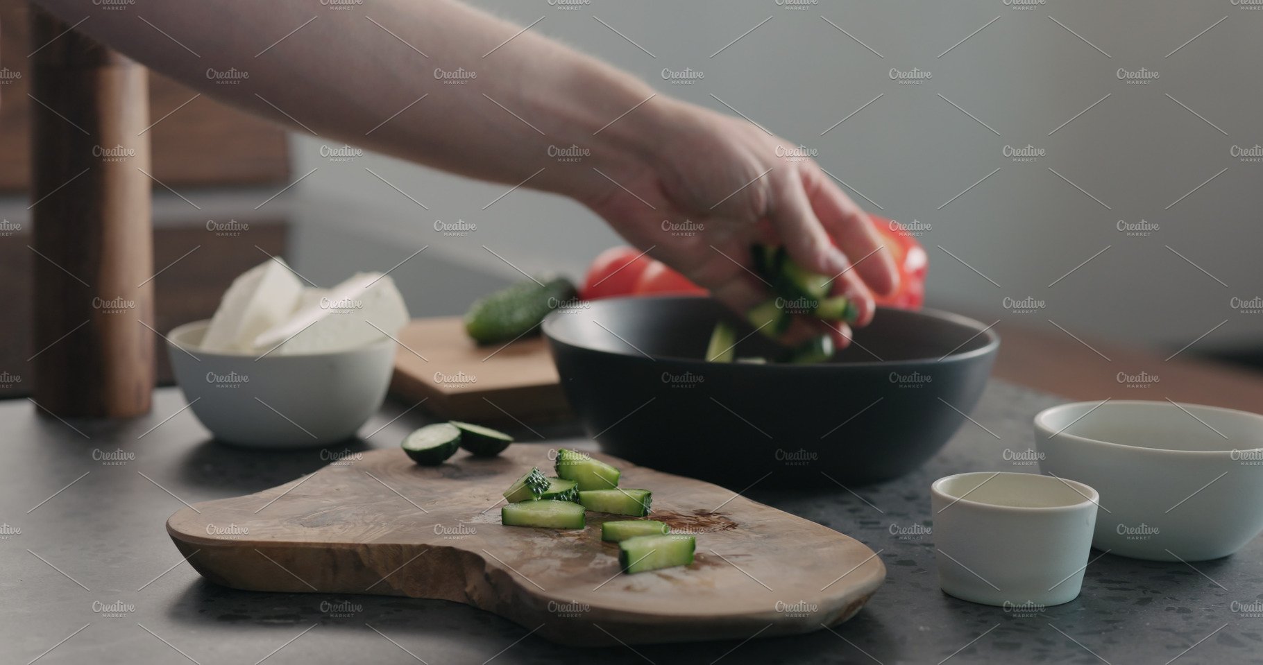 Man chopping cucumber on olive wood cover image.