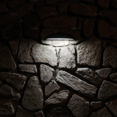 Lamp casting light on stone wall cover image.