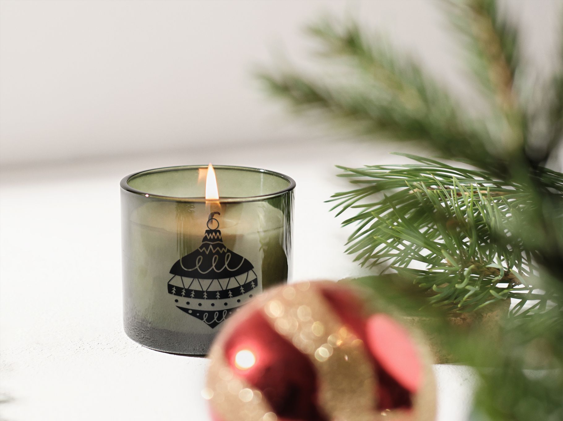 mockup of a scented candle placed on a christmas setting with christmas toy black silhouette design 133