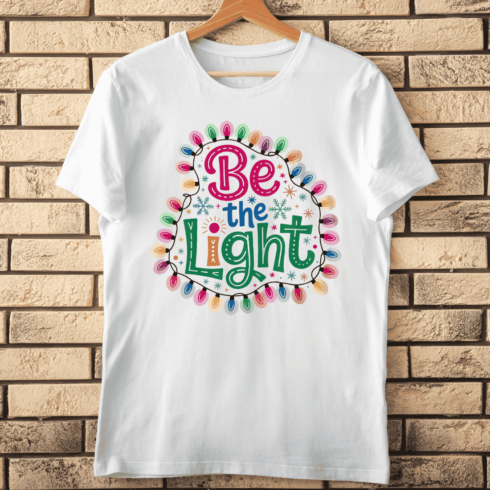Inspirational Quote Be The Light Holiday T-Shirt Design cover image.
