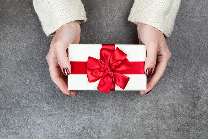 Present box with ribbon in woman hands.
