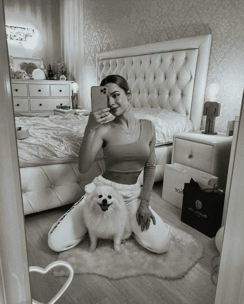 Black and white photograph taken by a girl in the mirror with a dog.