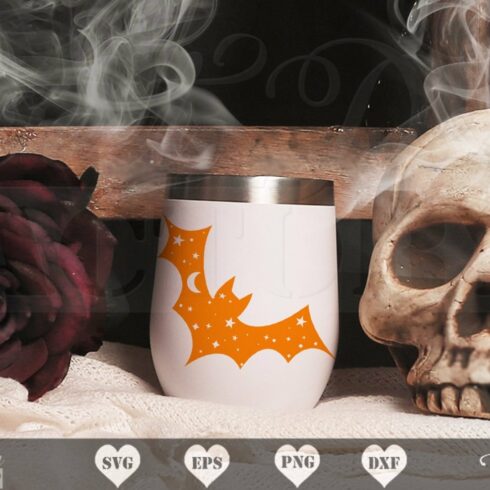 Skull sitting next to a cup on a table.