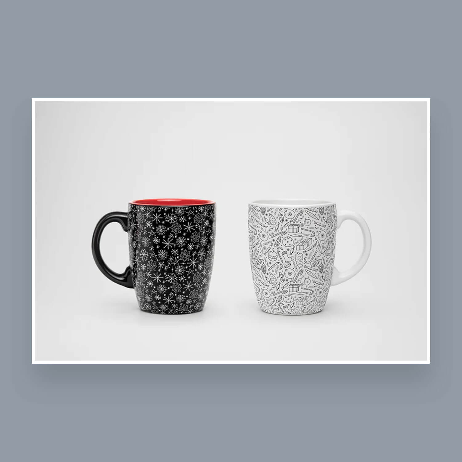A black cup with snowflakes and a white cup with Christmas sweets and gifts.