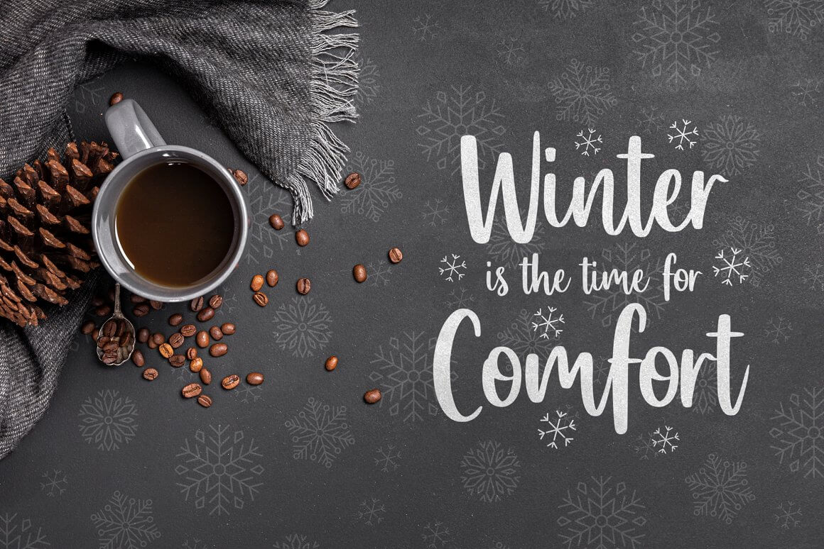 A cup of coffee with coffee beans on a table with a tablecloth in snowflakes, the inscription in white: Winter is the time for Comfort.