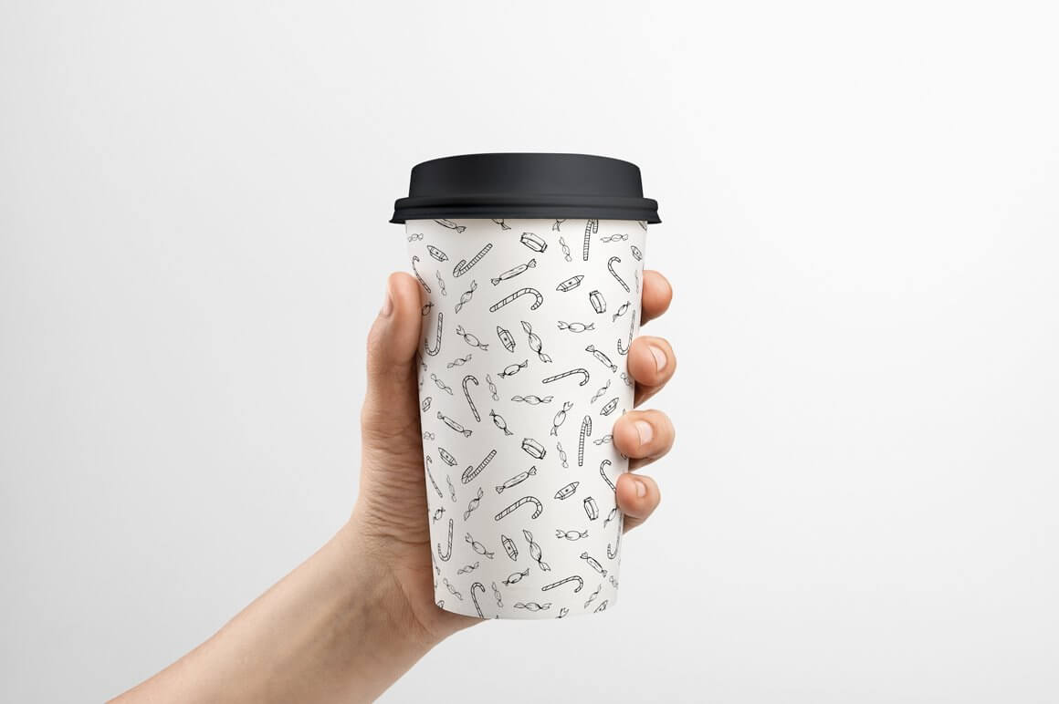 White glass of coffee with a small black pattern and a black lid.