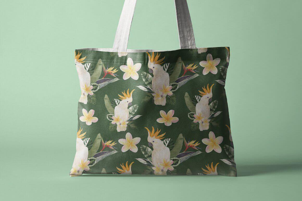 Green bag with painted parrots and large white tropical flowers.