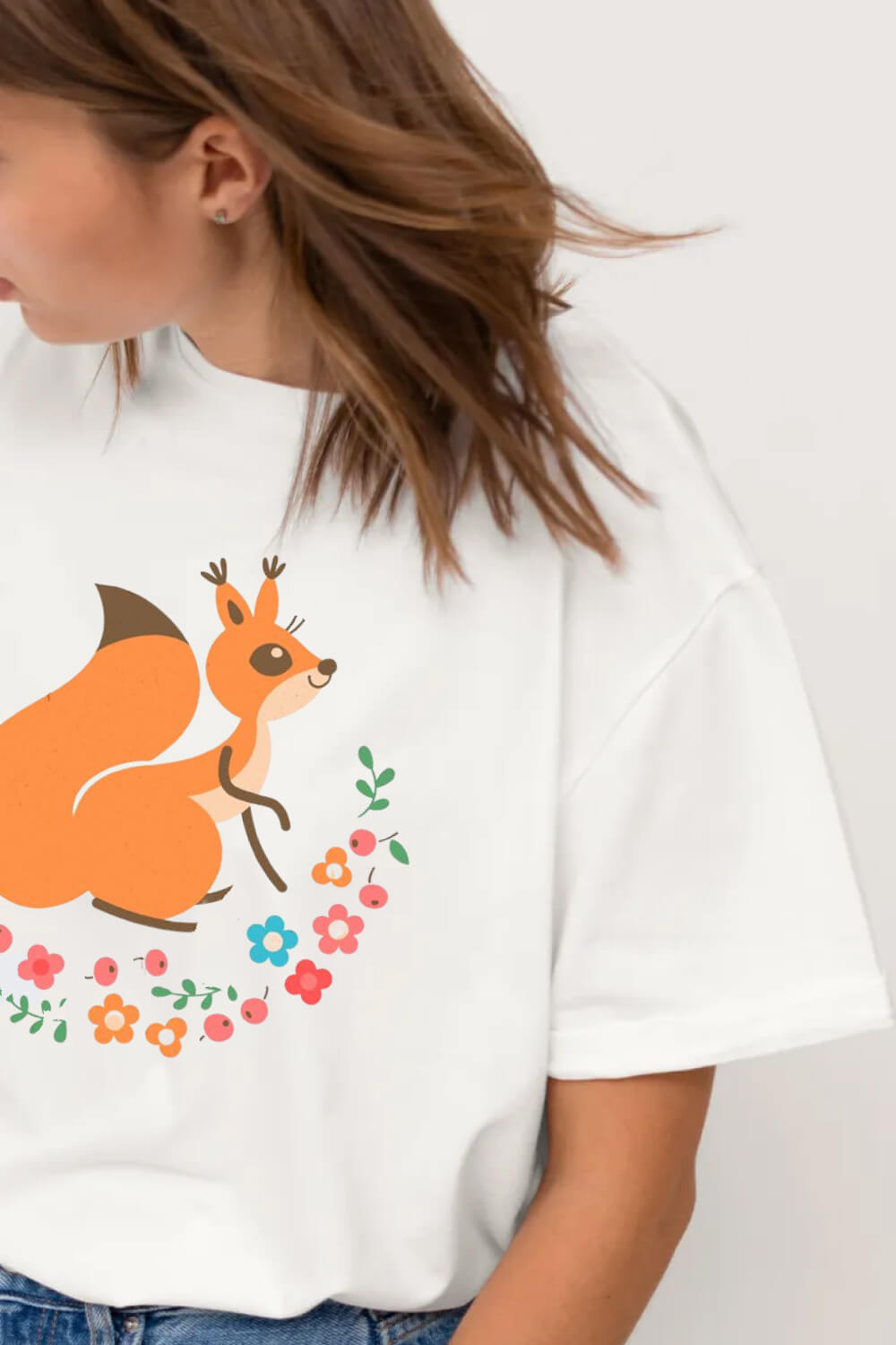 A funny squirrel with a fluffy tail surrounded by flowers and leaves painted on a girl's white t-shirt.