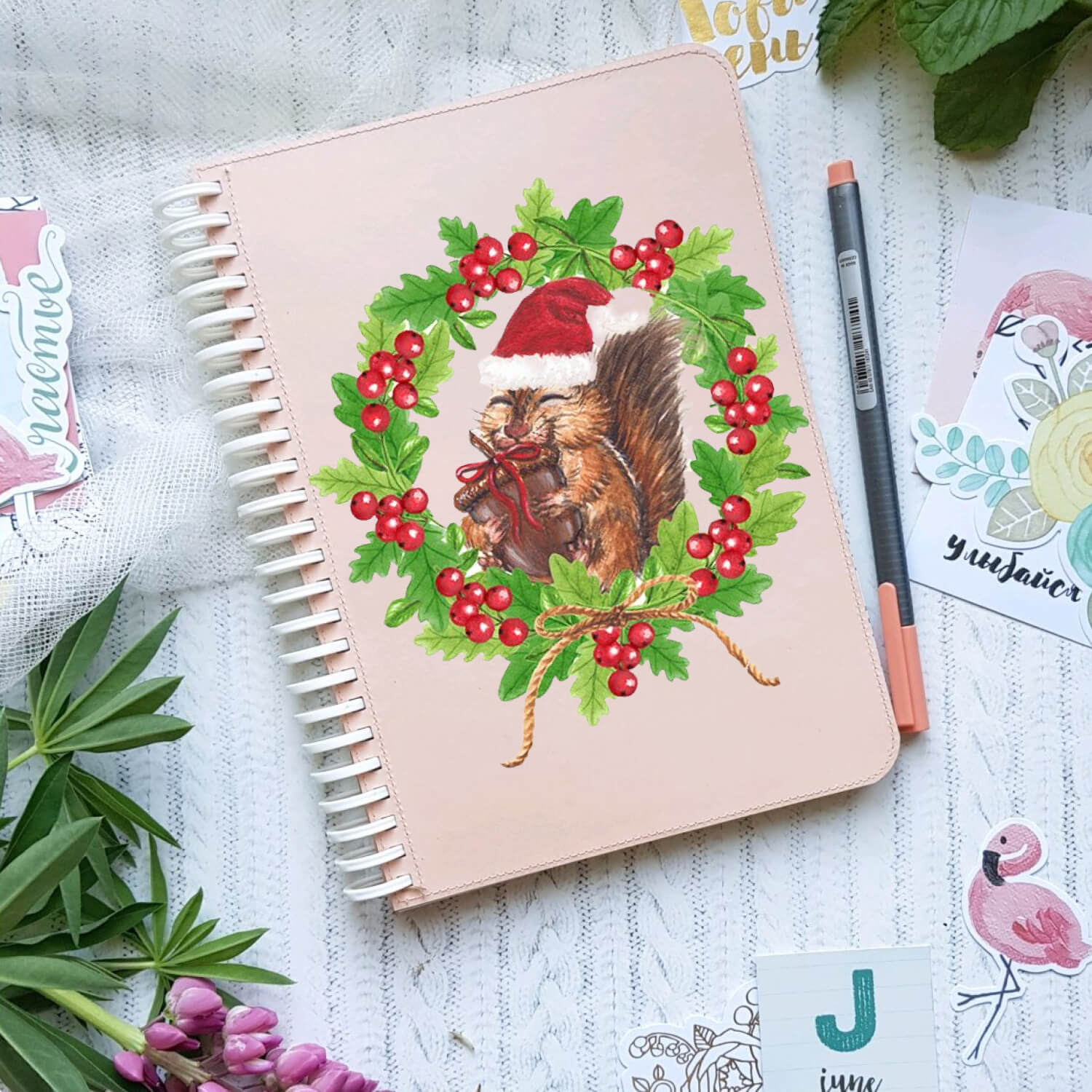 Happy squirrel in a christmas hat painted on the cover of a notebook.