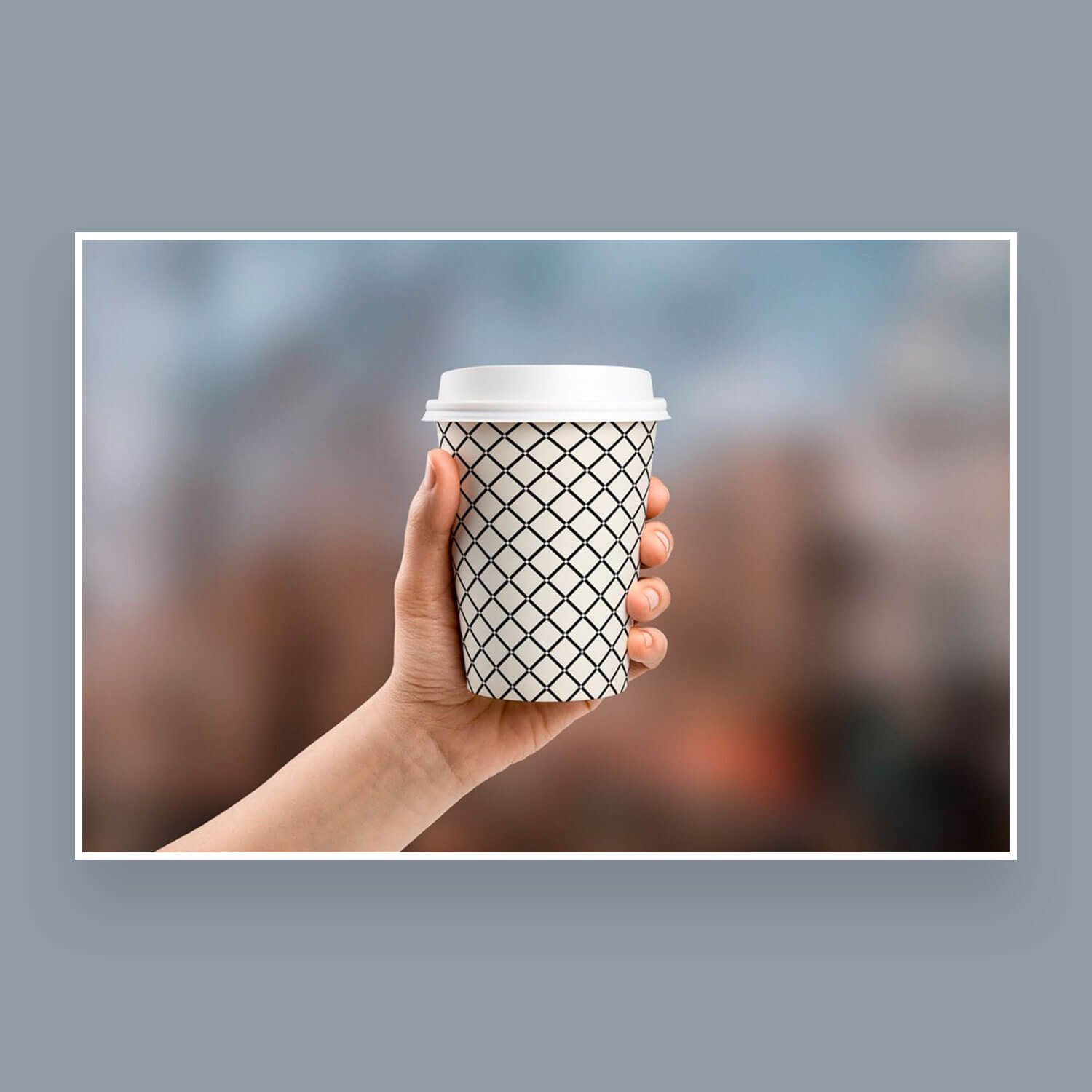 Seamless square and mesh patterns on a disposable cup with a lid on a rumpled, gray background.