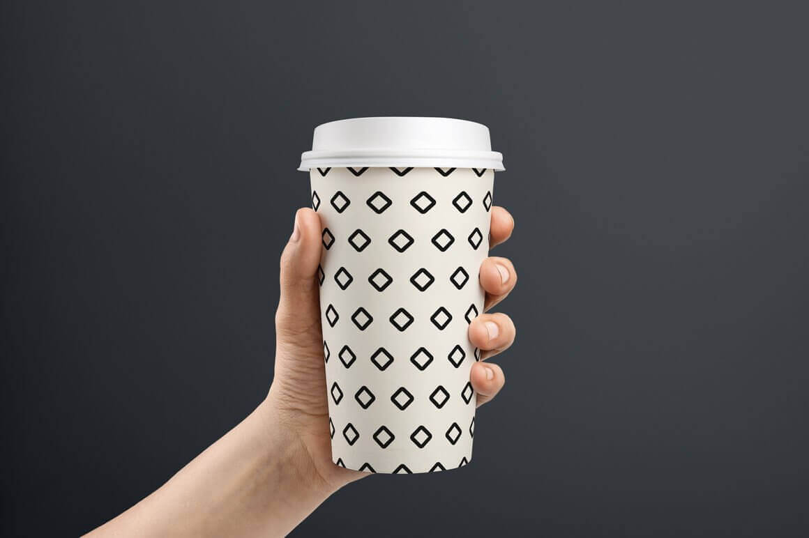 White coffee cup with geometric design, with rhombuses at a distance from each other.