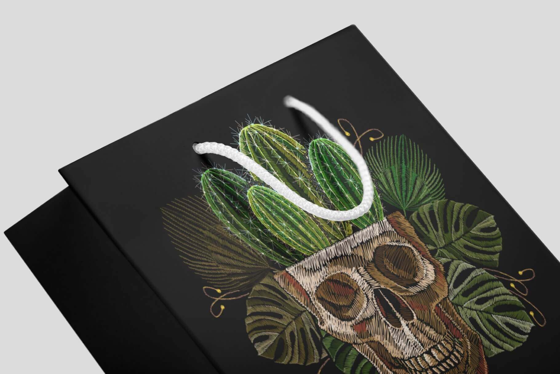 An embroidered skull that grows cacti on a black cardboard bag.
