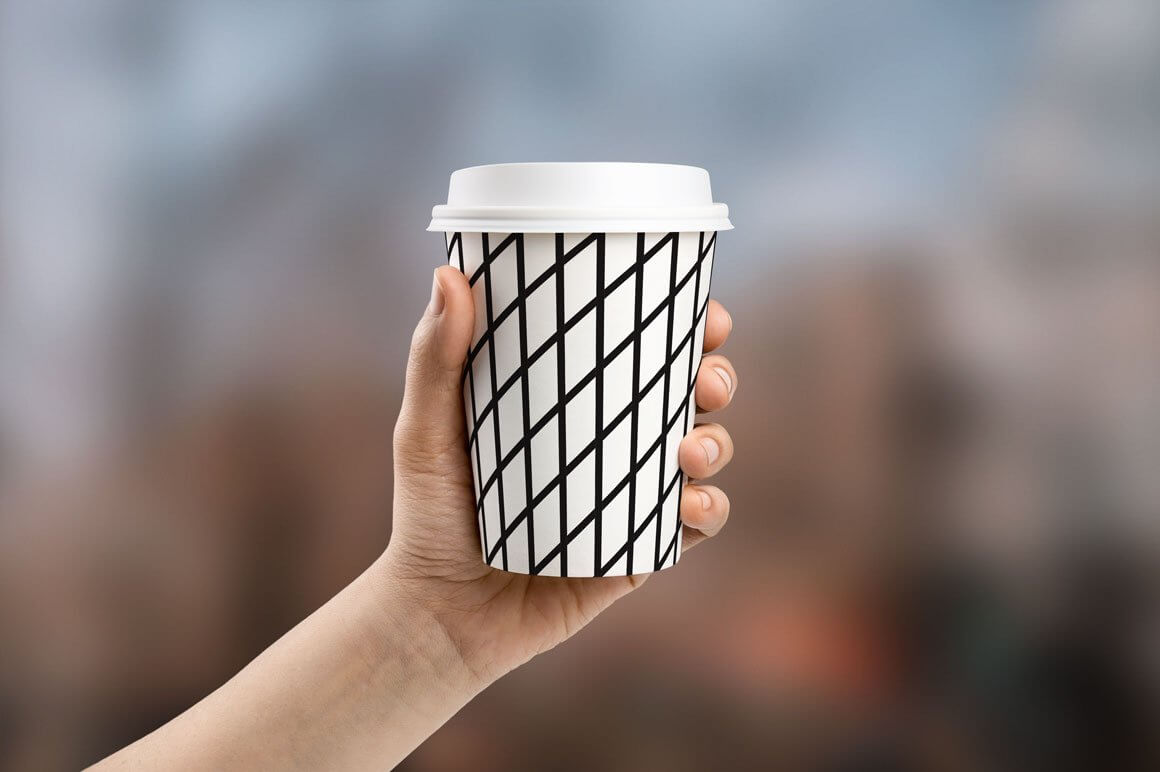 A glass of coffee with a geometric design on a blurred background.