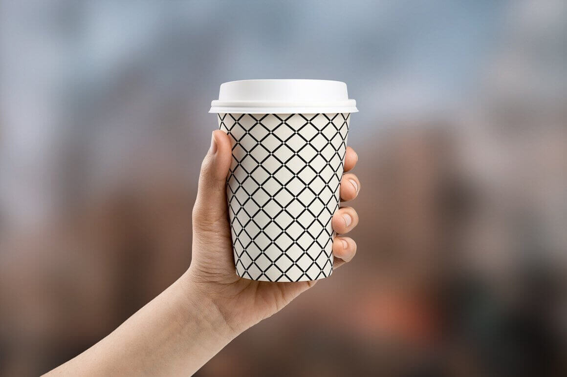On a white cup for coffee, lines are drawn that intersect each other, at the place of the intersection there is a small white dot.