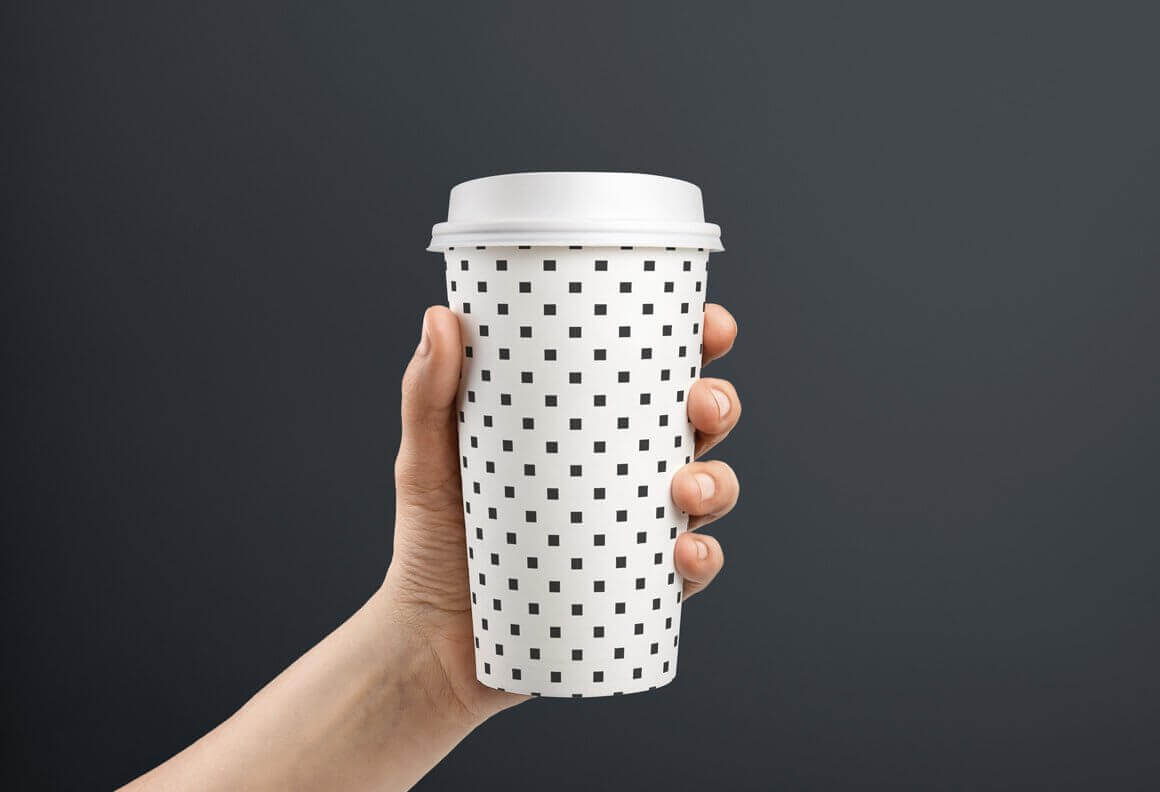 White coffee cup with geometric design and white lid.
