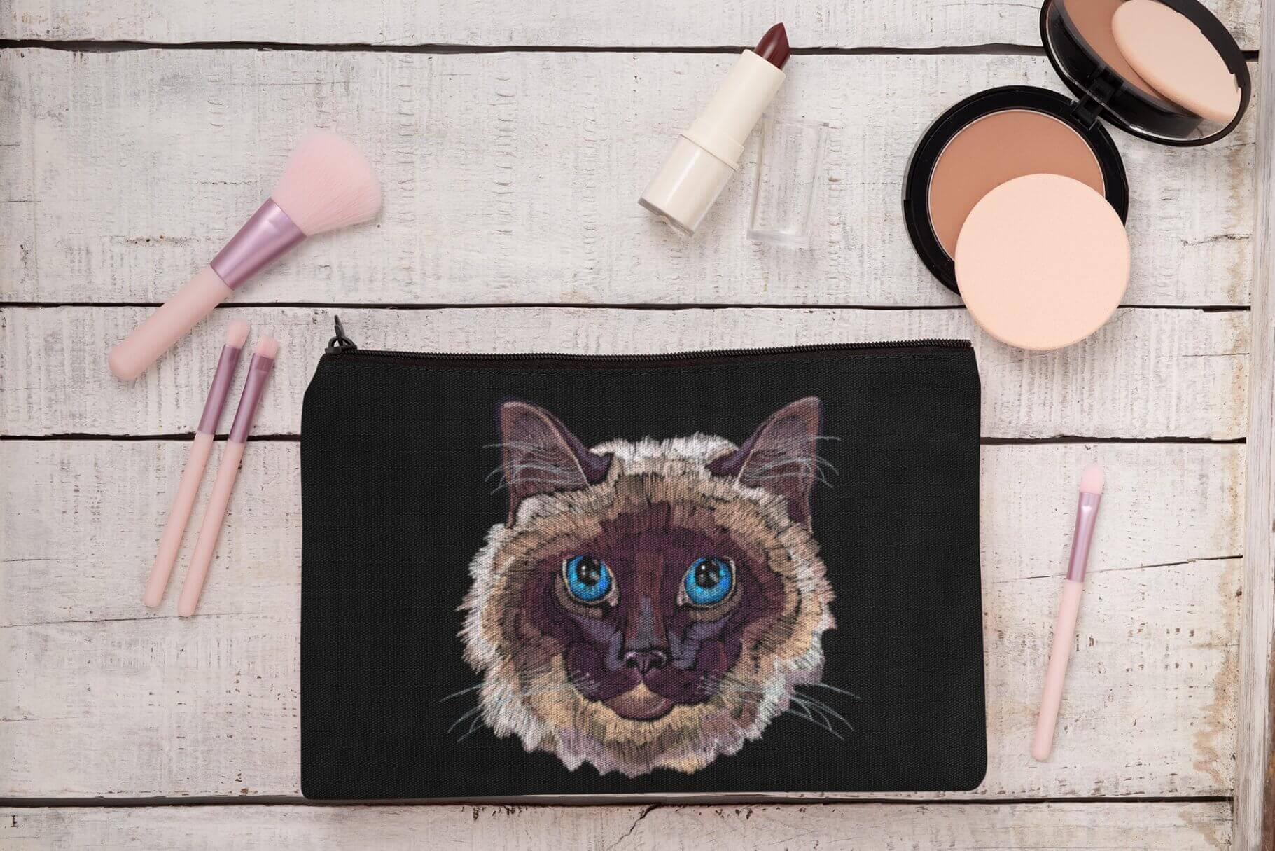 Embroidered Siamese cat with blue eyes on a cosmetic bag.