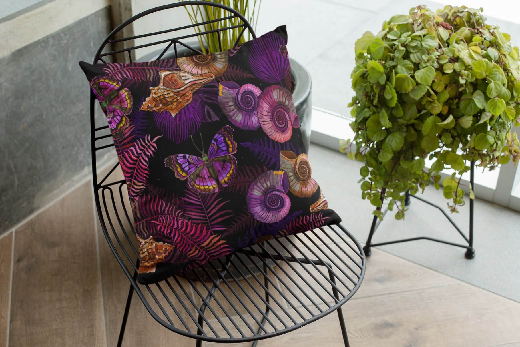 A black cushion with dark pink and purple prints on an iron chair.