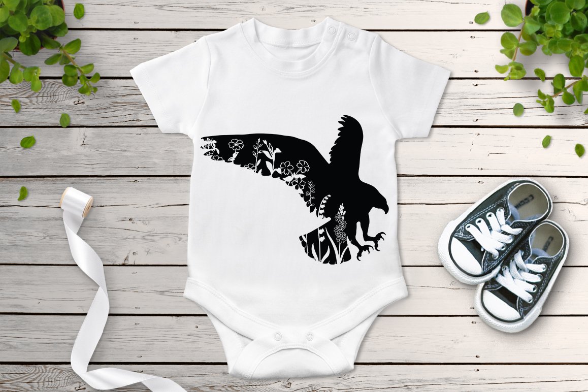 Baby bodysuit with an eagle on it next to a pair of sneakers.