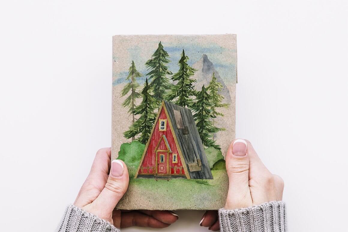 In the hands of a picture of a forest and a small house.