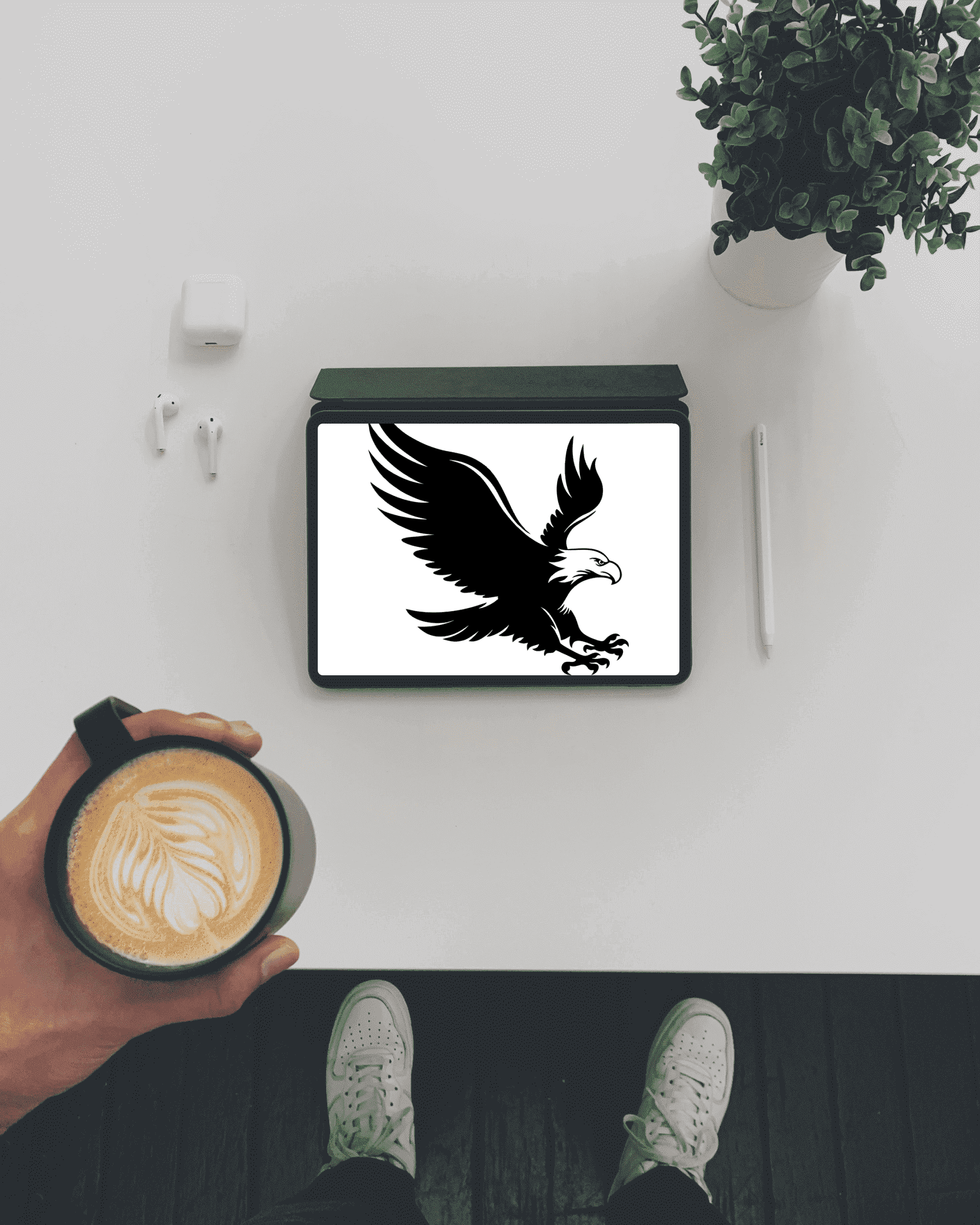 Person holding a cup of coffee in front of a picture of an eagle.