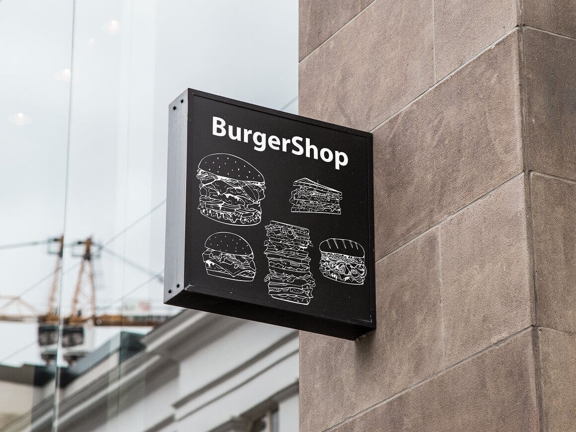 Burger shop signboard mockup on a black background on the wall.