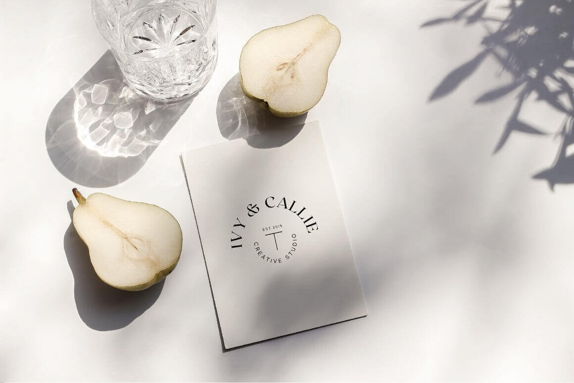 A cardboard card with a logo, a cut pear lies on a white table.
