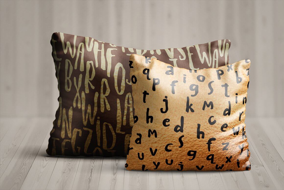 Two pillows in beige and brown are decorated with letters.