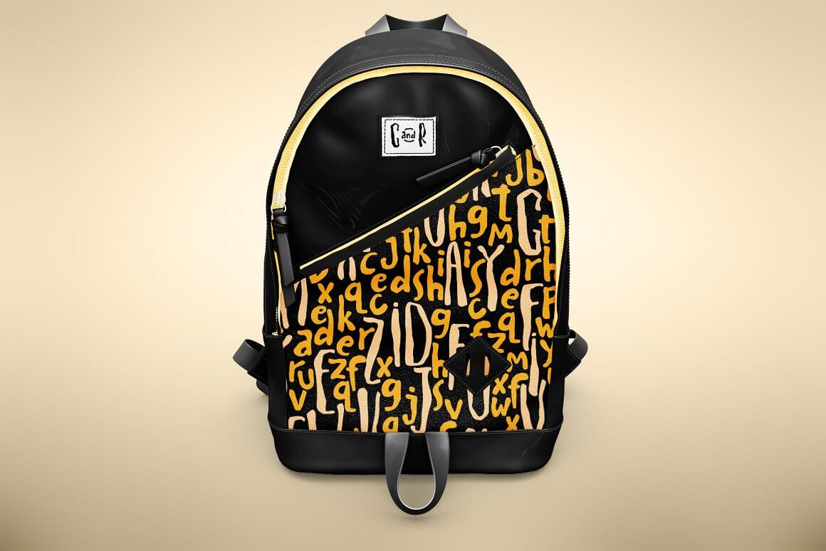 Black backpack with yellow letters on a beige background.