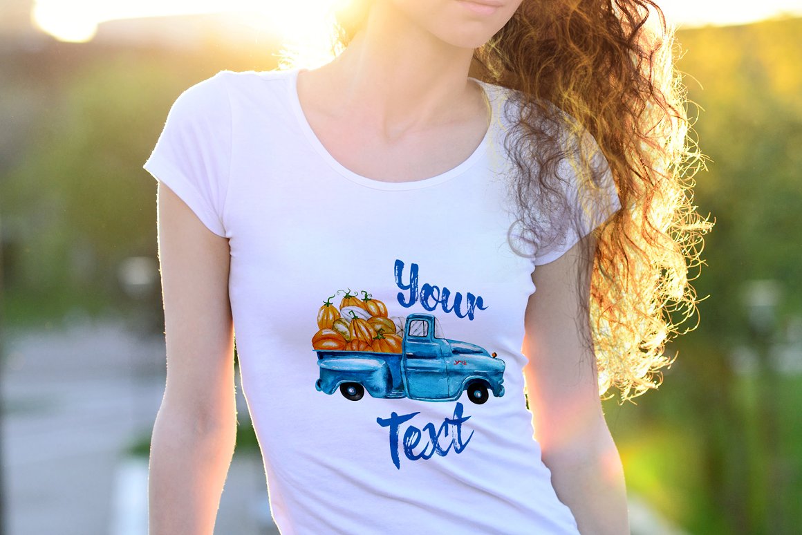 A white t-shirt with a picture of a blue truck full of pumpkins.