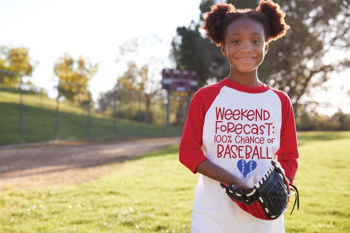 Color Girl in a baseball t-shirt with a glove and a ball on the background of the field.