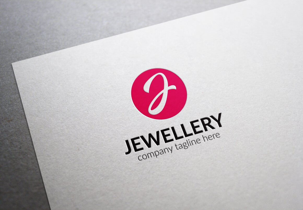 A large red J jewelry logo and the name below the logo on a gray piece of paper on a gray table.