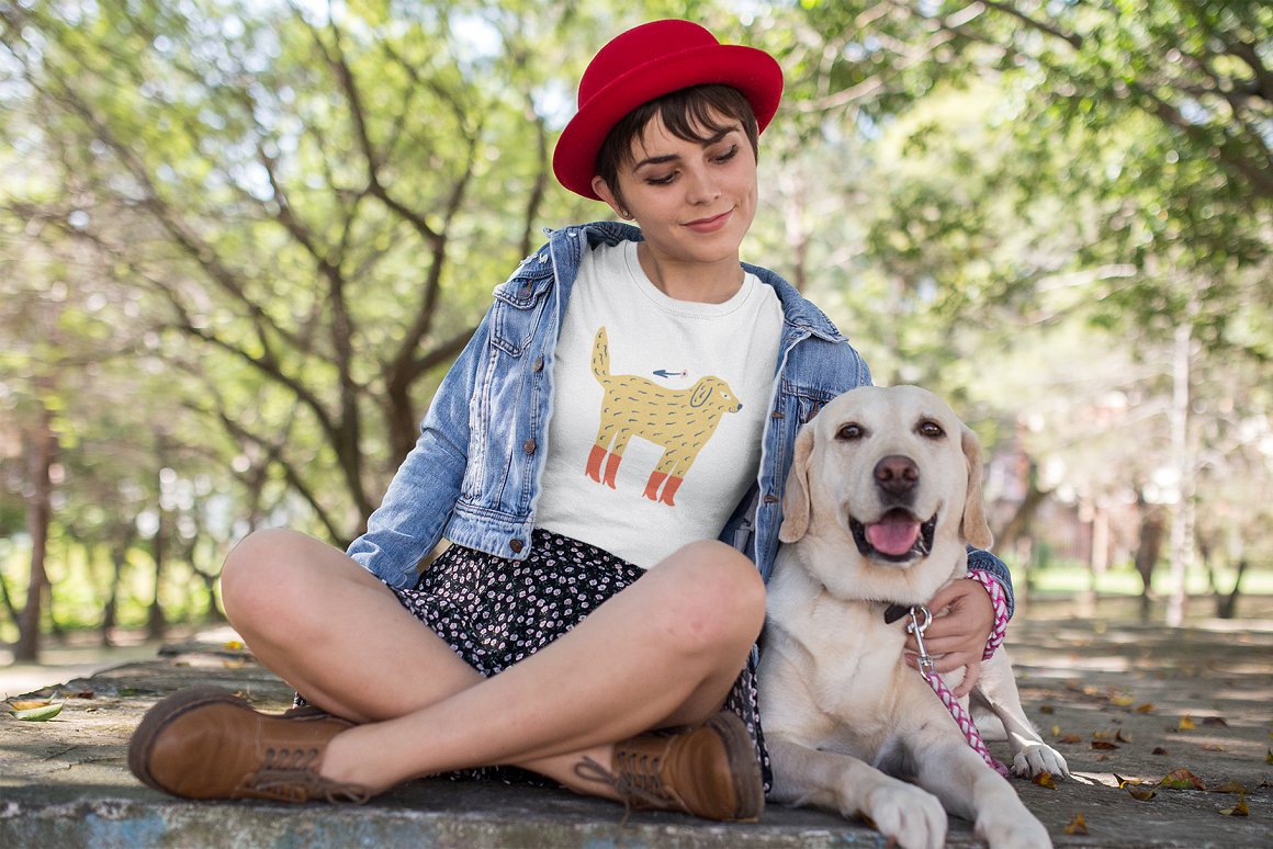A girl with a red hat hugs a dog in the park.