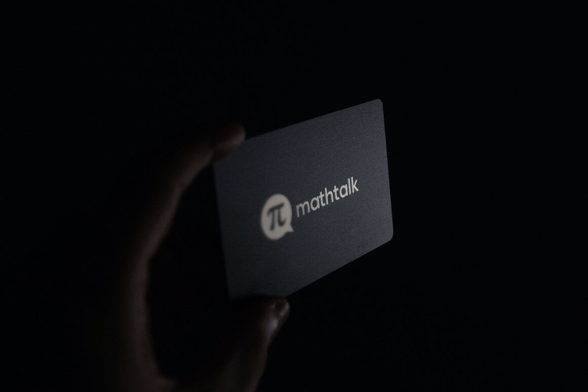 Stylish black business card with a light gray Math Talk logo in hand on a black background.
