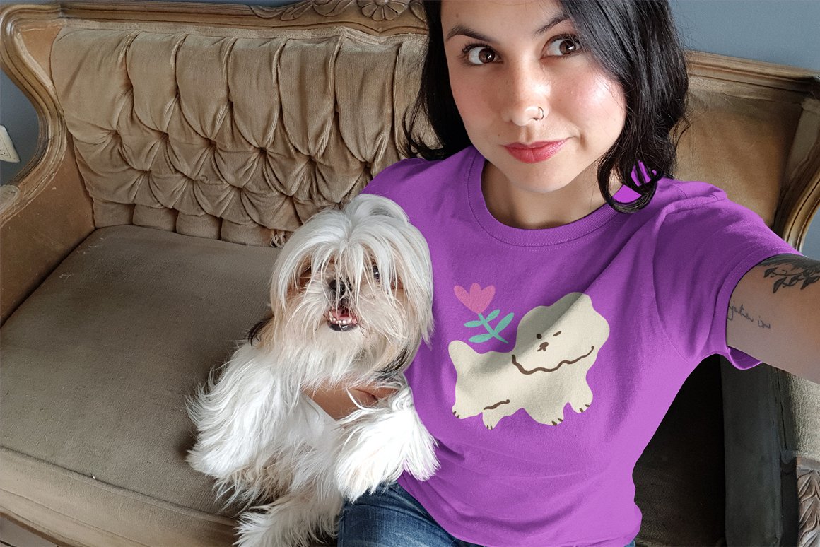 The girl is holding a dog in her arms, and the exact same dog is depicted on her T-shirt.