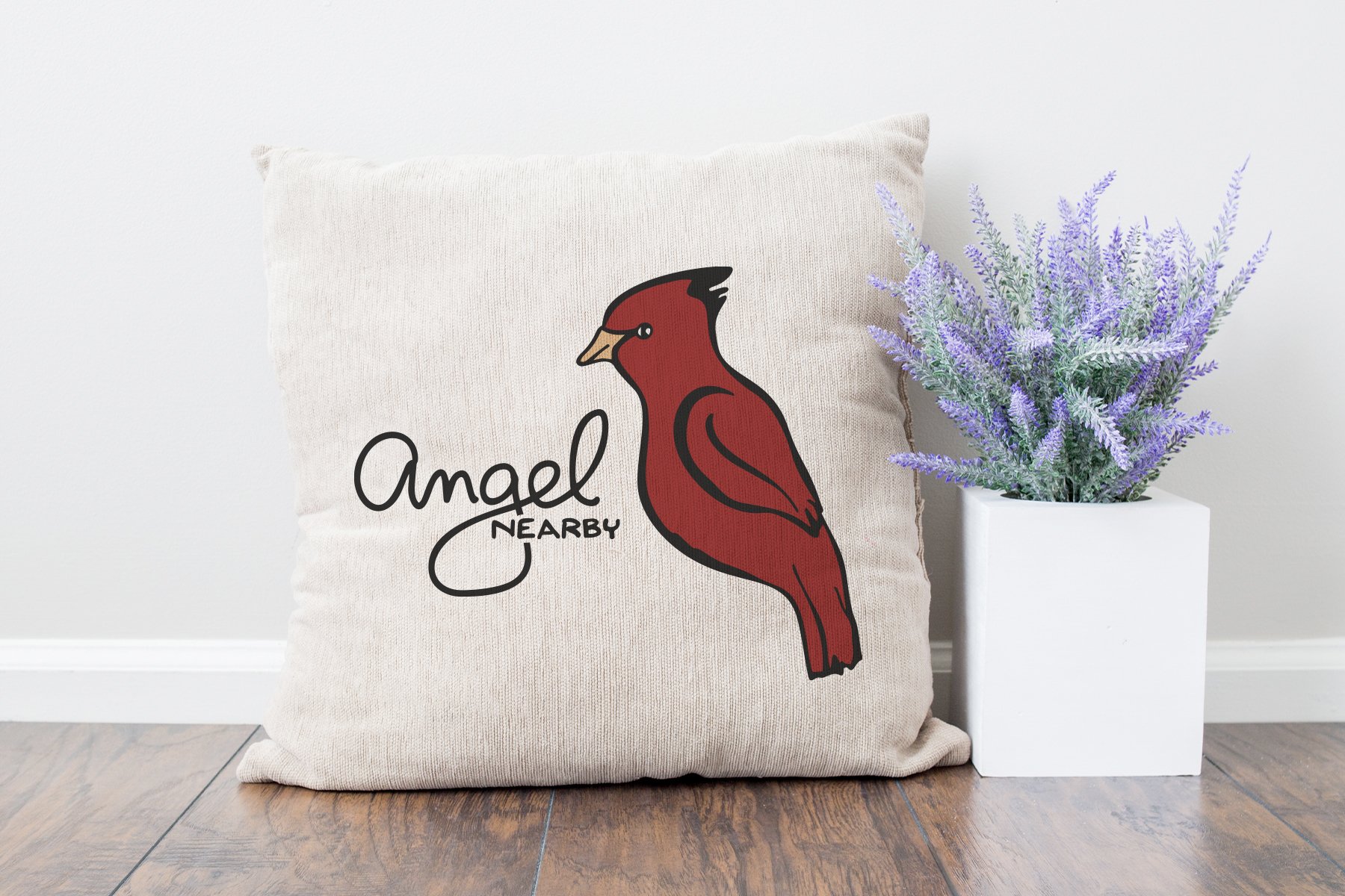 Pillow with a cardinal on it next to a potted plant.