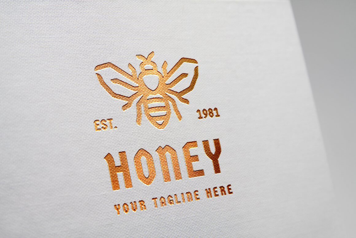 Image of a logo with a golden bee and the inscription "Honey" on a white fabric background.