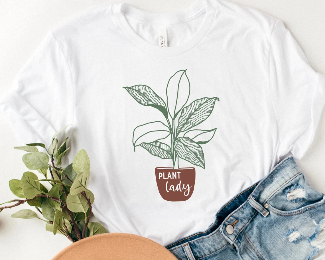A flower in a vase on a print on a white t-shirt.