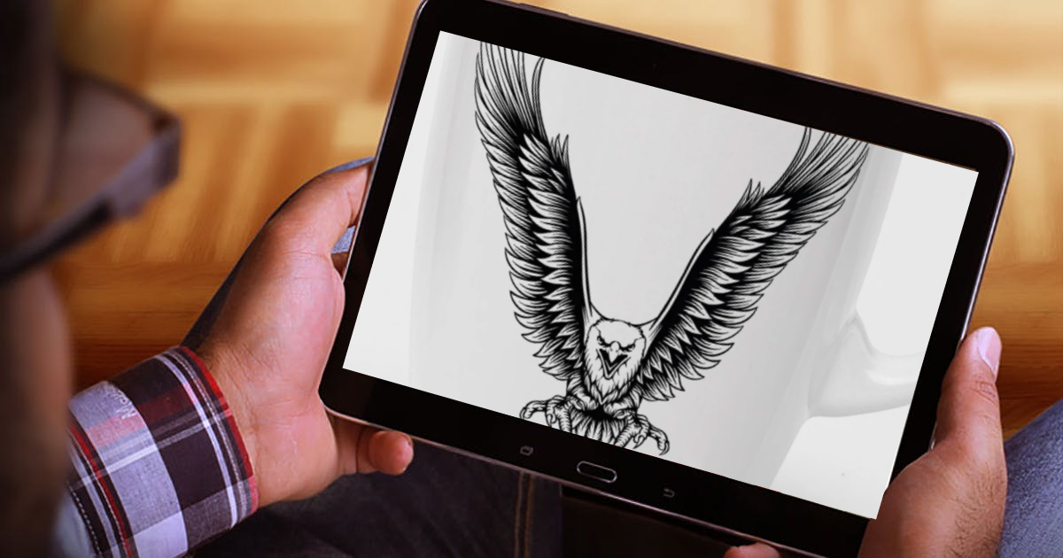 Person holding a tablet with a drawing of an eagle on it.