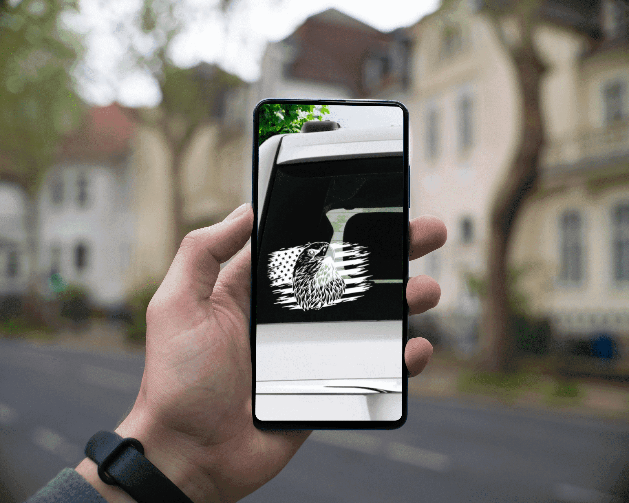 Hand holding a cell phone with a picture of a house on the screen.