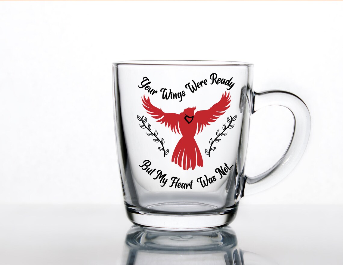 Glass mug with a red bird on it.