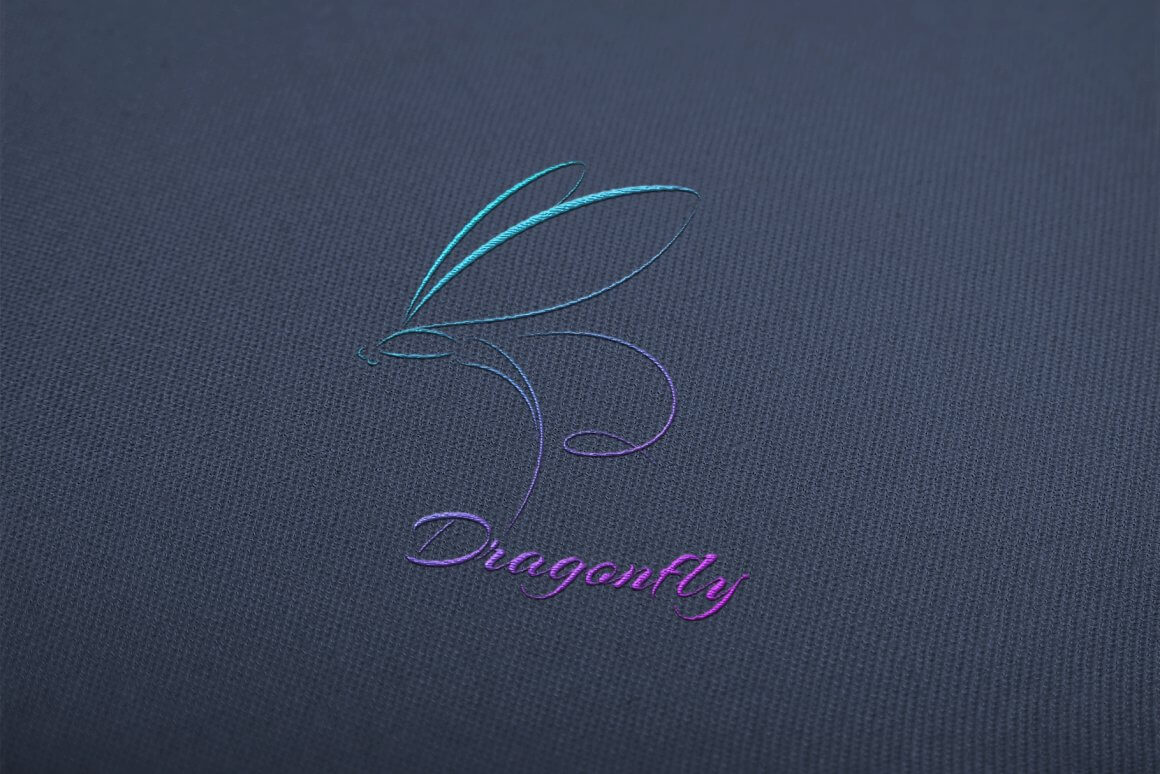 Logo with gradient from turquoise to purple dragonfly on gray fabric.